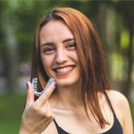 Red-haired woman smiling and holding an Invisalign aligner