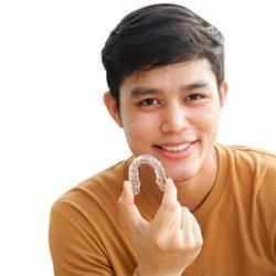 Close-up of teenage boy holding an Invisalign aligner