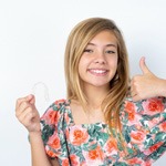 Teenage girl holding Invisalign and giving thumbs up