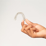 Close-up of hand holding an Invisalign aligner